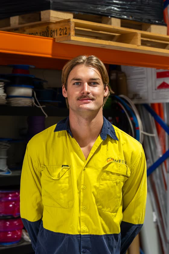 Tradie in a yellow work shirt in his workshop