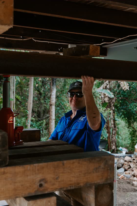 Builder fixing timber framing under a house