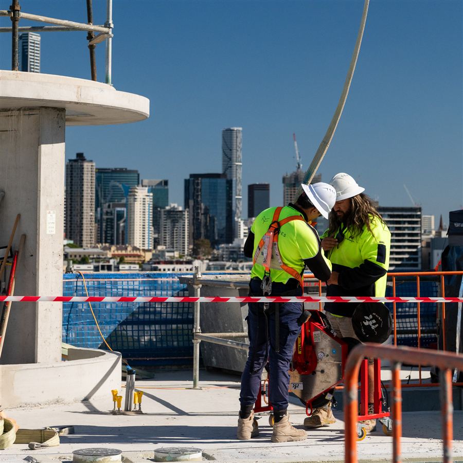 Construction crew on a high-rise rooftop with the Brisbane skyline behind